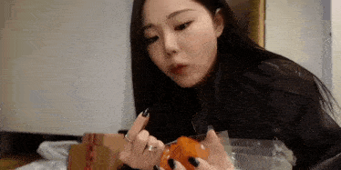 a woman is sitting on a bed eating a candy .