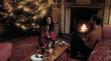 a man and a woman are sitting in front of a fireplace