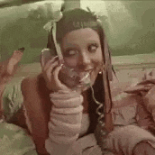 a woman is laying on a bed talking on a telephone with her eyes closed .