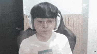 a boy wearing headphones and glasses is sitting in a chair .