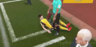 a soccer player is laying on the ground while a referee looks on