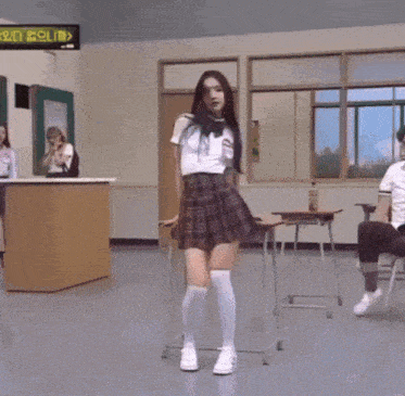 a girl wearing a plaid skirt and a white shirt has a name tag that says ' a ' on it