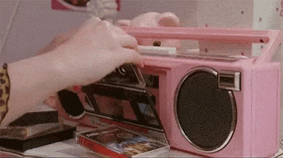 a woman is using a pink boombox to play cassette tapes .