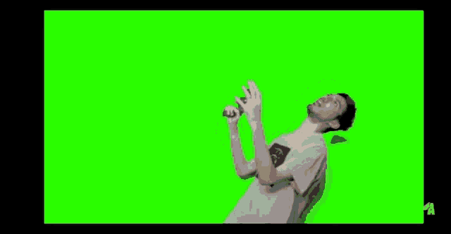 a man is standing in front of a green screen holding a microphone in his hand .