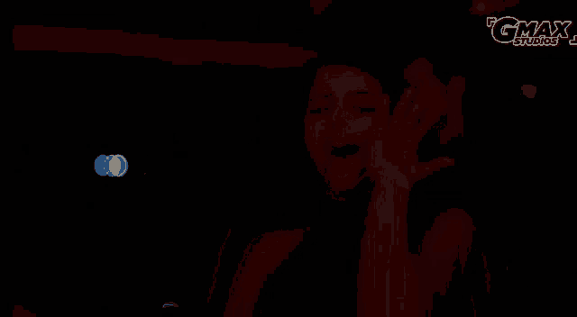 a woman dancing in a dark room with gmax studios written on the bottom right