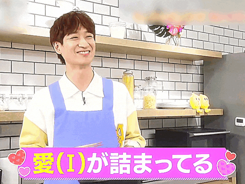 a man wearing an apron is smiling in a kitchen with a sign that says " i " on it