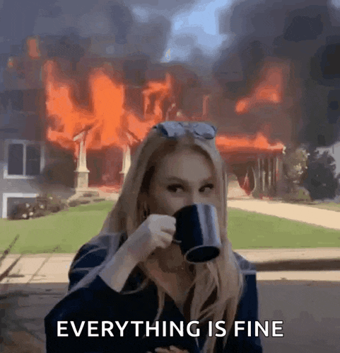 a woman is drinking a cup of coffee in front of a house that is on fire .