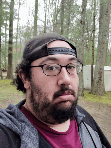 a man with a beard and glasses wearing a hat