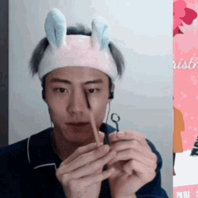 a young man wearing a headband with bunny ears is holding a pencil in his hands .