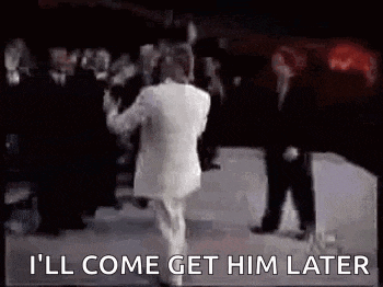 a man in a white suit is dancing in front of a crowd of people .