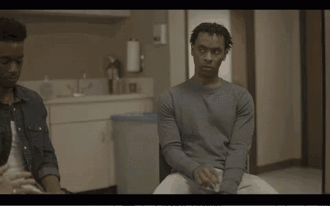 two men are sitting next to each other in a room and one of them is talking to the other .