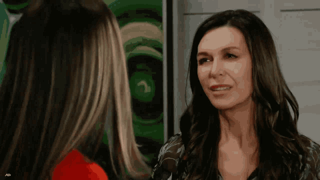 two women are standing next to each other in front of a painting
