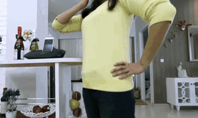 a woman in a yellow sweater stands in a living room