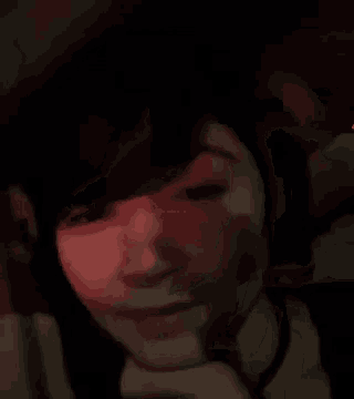 a close up of a woman 's face in a dark room with red lights behind her .