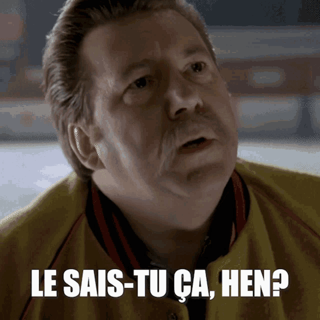 a man with a mustache is wearing a yellow jacket with the words le sais-tu ca hen written on it