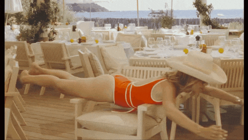 a woman in an orange swimsuit is laying on her back in a chair