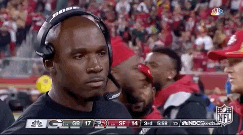 a man wearing headphones is watching a football game on tv .