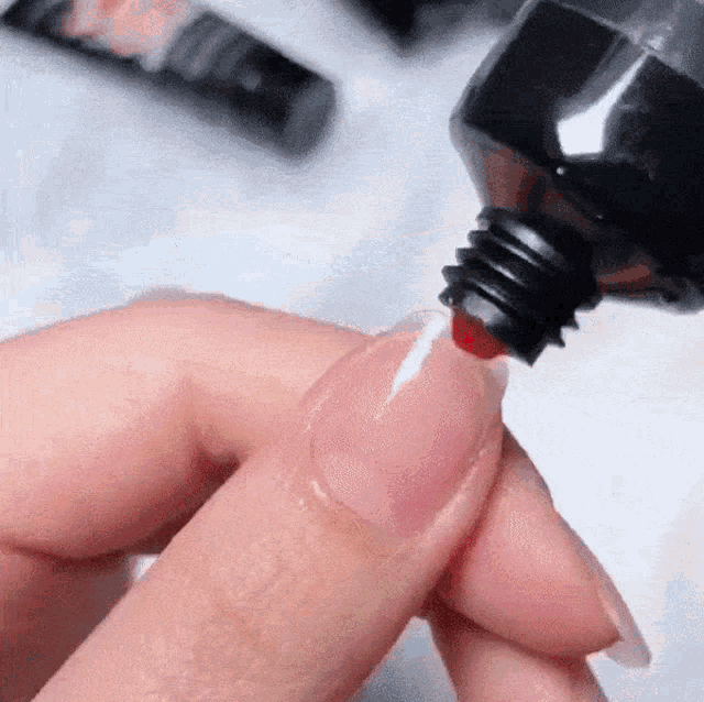 a woman is applying red nail polish to her nails