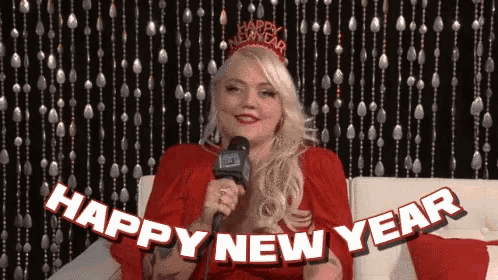 a woman wearing a red dress and a happy new year crown holds a microphone