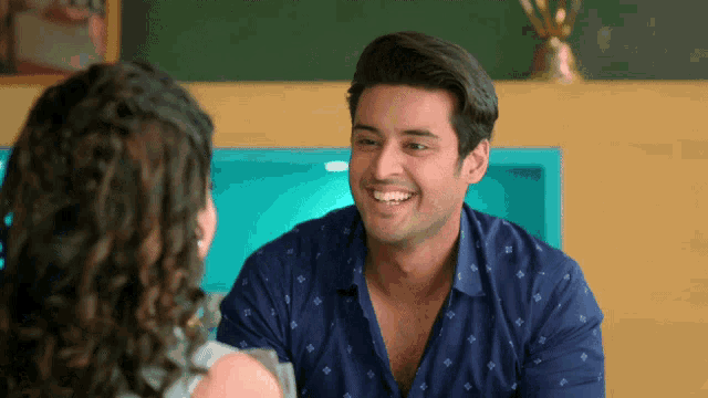 a man in a blue shirt smiles while looking at a woman