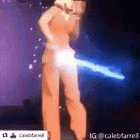 a woman in an orange jumpsuit is standing on a stage with a blue light behind her