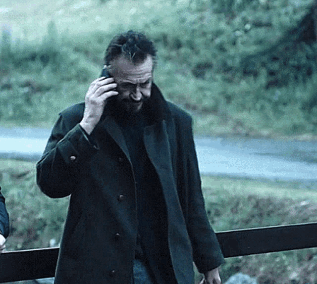 a man wearing a black coat is talking on a cell phone