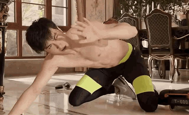 a shirtless man is kneeling on the floor in front of a t-600 machine