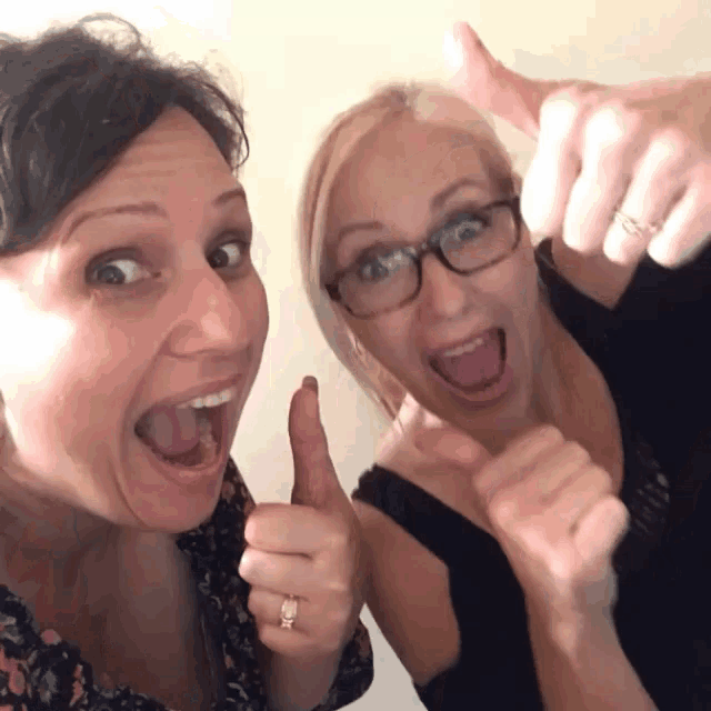 two women are giving each other a thumbs up sign
