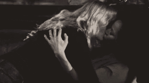 a black and white photo of a couple kissing in a car .