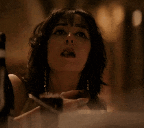 a woman is sitting at a table with a glass of wine