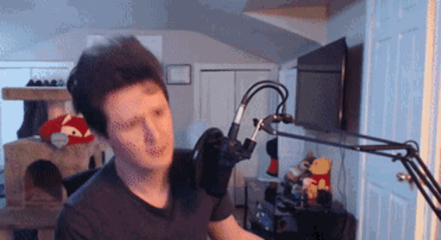 a man in a black shirt stands in front of a microphone in a room