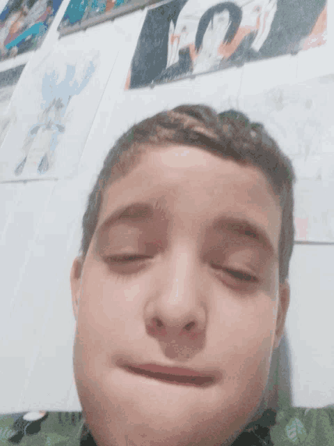 a close up of a boy 's face with his eyes closed in front of a wall with drawings on it