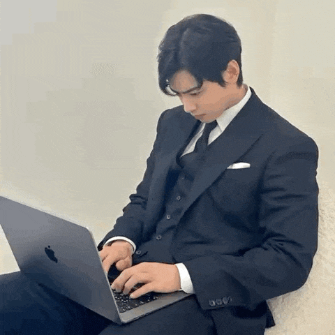 a man in a suit is typing on a laptop computer .