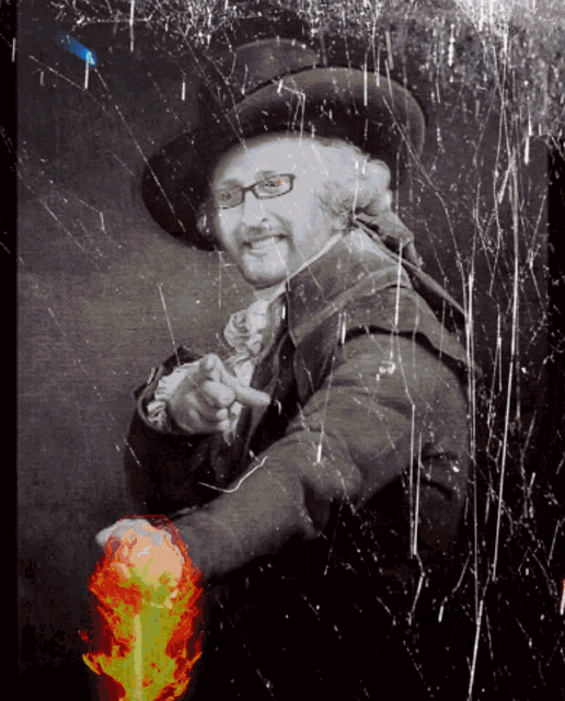 a man wearing glasses and a hat is pointing at a fireball