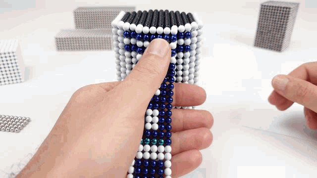 a person is holding a string of blue and white beads with the letter t on it