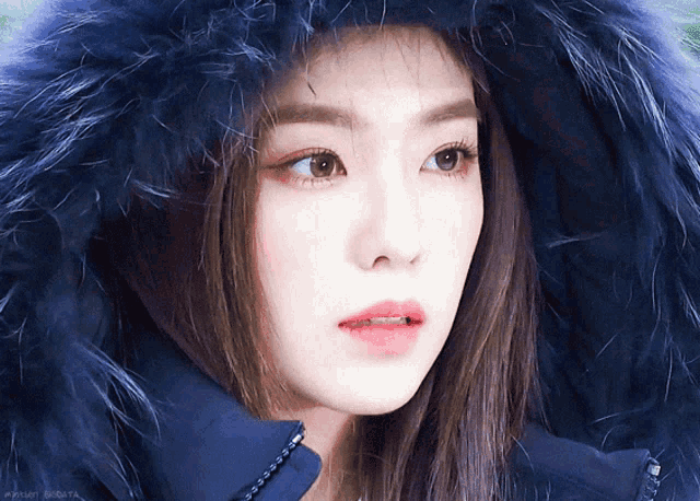 a close up of a woman wearing a blue coat with a fur hood