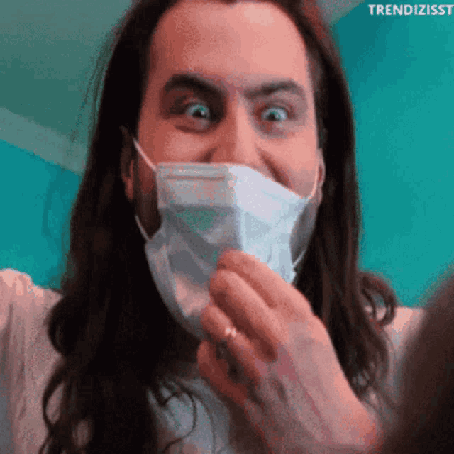 a man with long hair wearing a face mask with trendizisst written on the bottom right