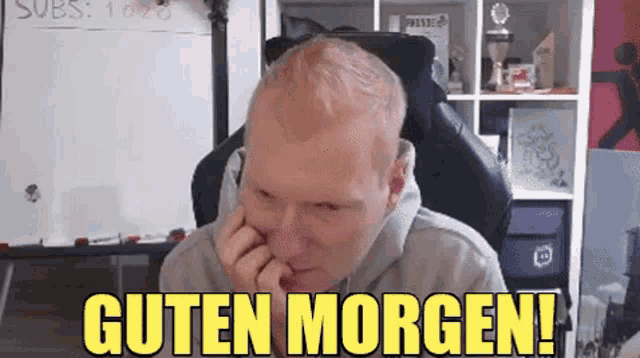 a man is sitting in a chair with his head resting on his hand and the words guten morgen written above him .
