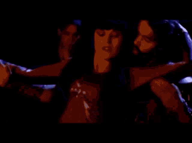 a man and a woman are dancing in a dark room . the woman is wearing a red top .