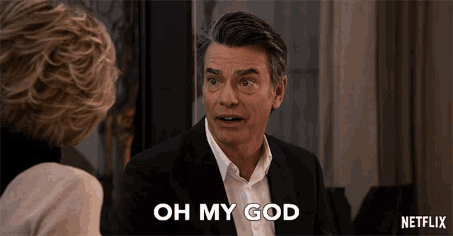 a man in a suit says oh my god while talking to a woman