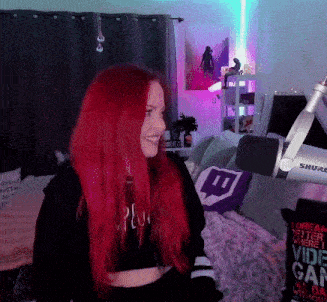 a woman with red hair stands in front of a shure microphone in a room