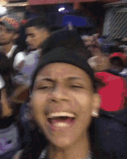 a man wearing a black hat is laughing in a crowd of people