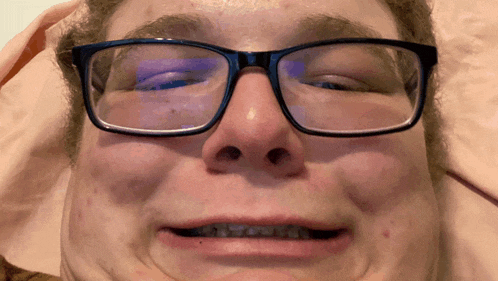 a close up of a person wearing glasses with their eyes closed