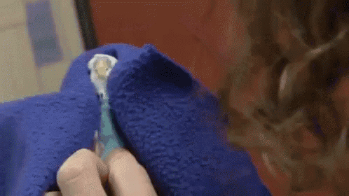 a person is holding a blue towel over their face and cleaning it .