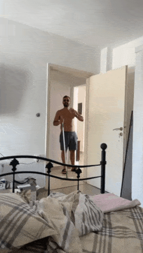 a man without a shirt is standing in front of a mirror in a bedroom