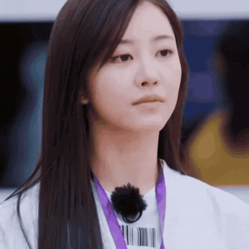 a woman wearing a white jacket and a purple lanyard