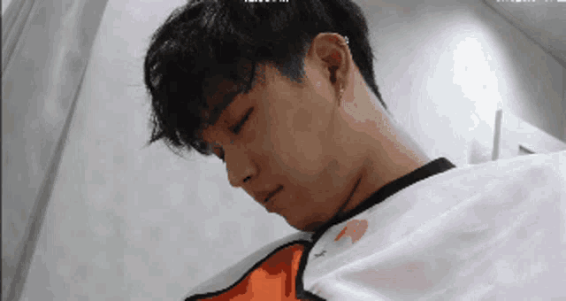 a man with a piercing in his ear is laying down with his eyes closed