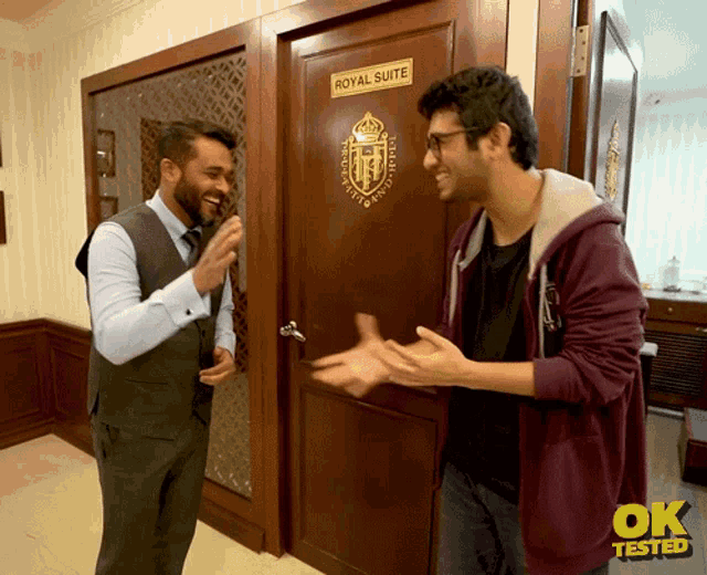 two men standing in front of a door that says royal suite