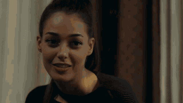 a woman with a ponytail looks at the camera with a smile on her face