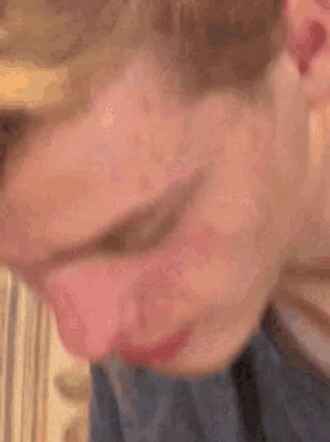 a close up of a person 's face with a blue shirt